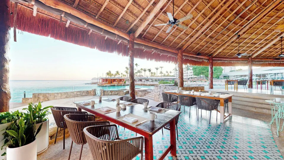 Thatched-roof seaside dining tables with patterned tile floor at InterContinental Presidente Cozumel Resort Spa