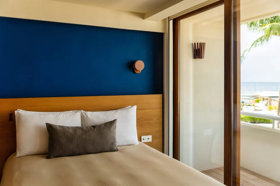 Bedhead and balcony door with partial ocean view in a Classic Room at InterContinental Presidente Cozumel Resort Spa