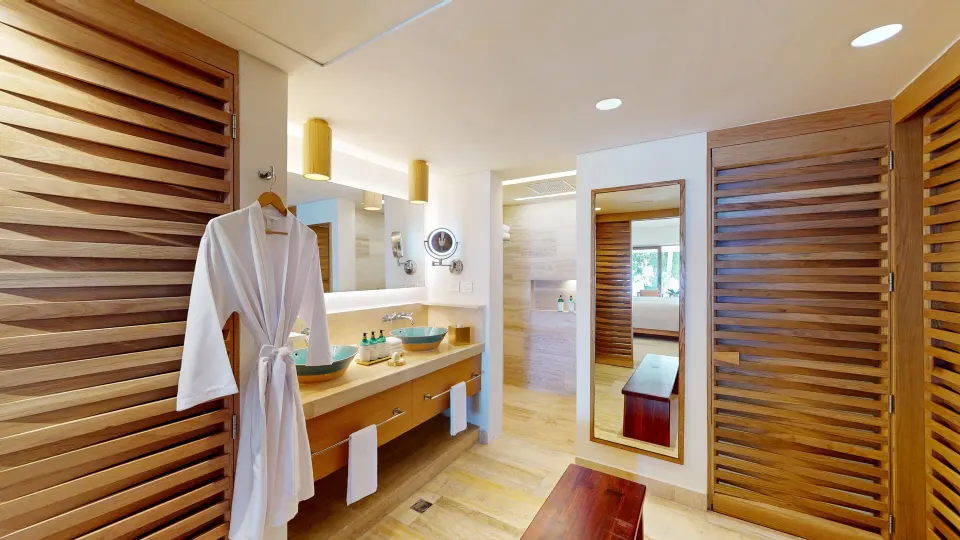 Junior suite bathroom vanity with twin sinks and wooden louvered doors at InterContinental Presidente Cozumel Resort Spa