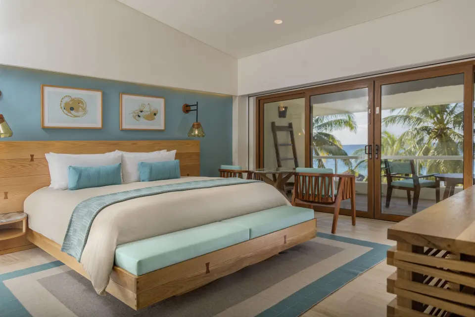 Premium room king bed with bench and balcony overlooking palms and ocean at InterContinental Presidente Cozumel Resort Spa