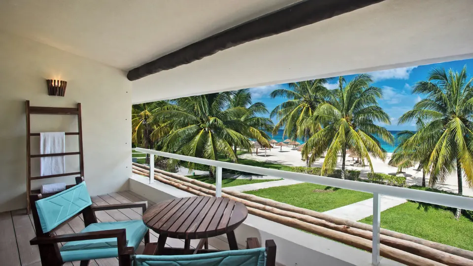 Balcony table and chairs overlooking palm trees and beach at InterContinental Presidente Cozumel Resort Spa