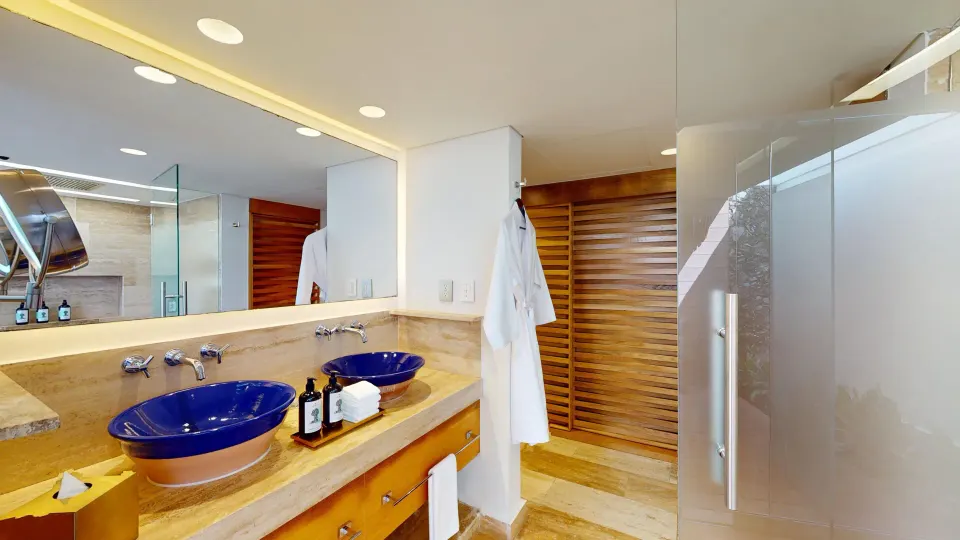 Guest bathroom double vanity with blue sinks and glass shower at InterContinental Presidente Cozumel Resort Spa