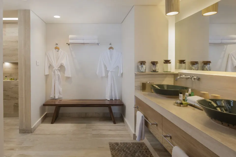 Bathroom with robes, bench and double sink at InterContinental Presidente Cozumel Resort Spa