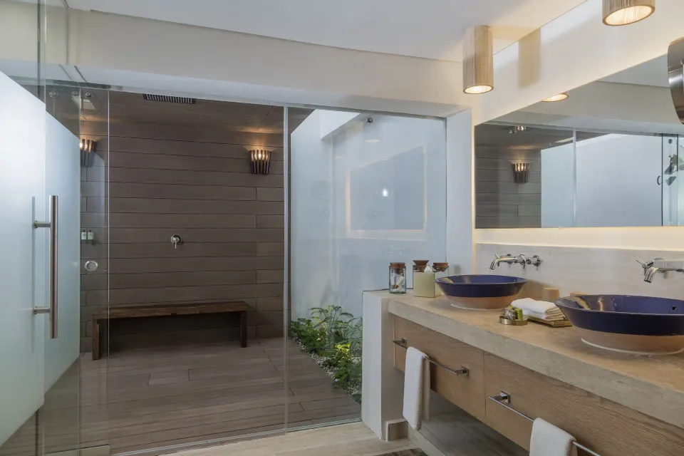 Bathroom with dual sinks and view through glass to outdoor shower courtyard at InterContinental Presidente Cozumel Resort Spa