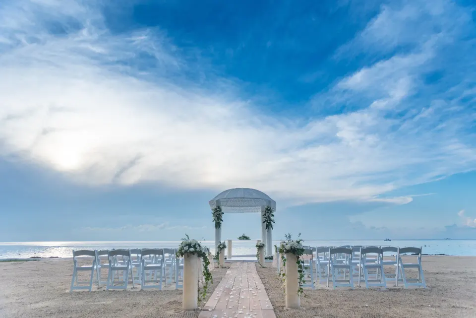 Beach wedding setup with aisle, white chairs and floral arch at InterContinental Presidente Cozumel Resort Spa