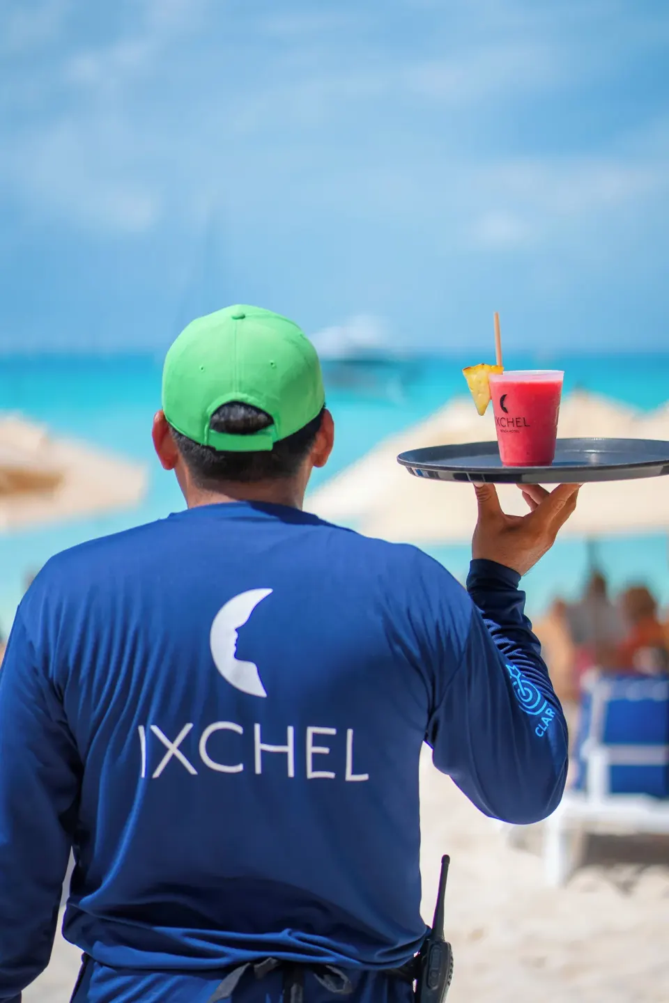 Beach server carries a pink drink on a tray at Ixchel Beach Hotel.