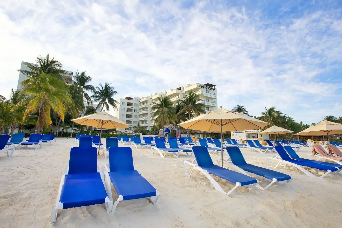 Blue lounge chairs and umbrellas line the sandy beach at Ixchel Beach Hotel.