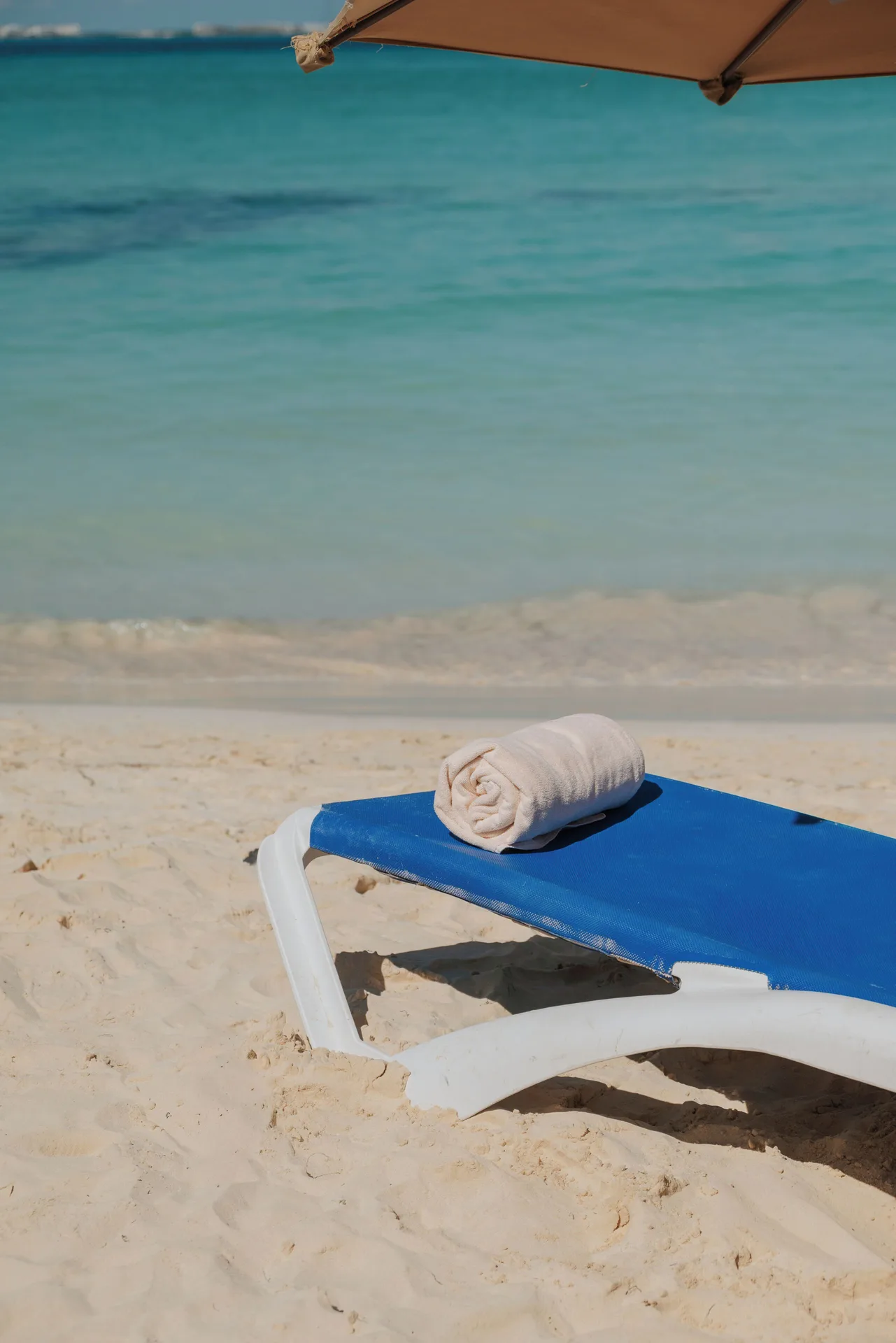 Blue beach lounger with a rolled towel by the water at Ixchel Beach Hotel.