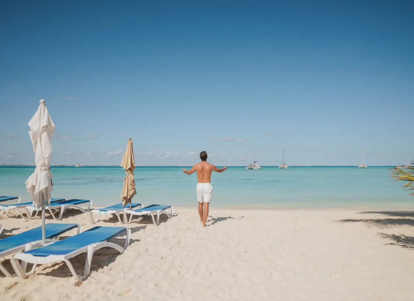 Beach loungers and umbrellas face turquoise water at Ixchel Beach Hotel.