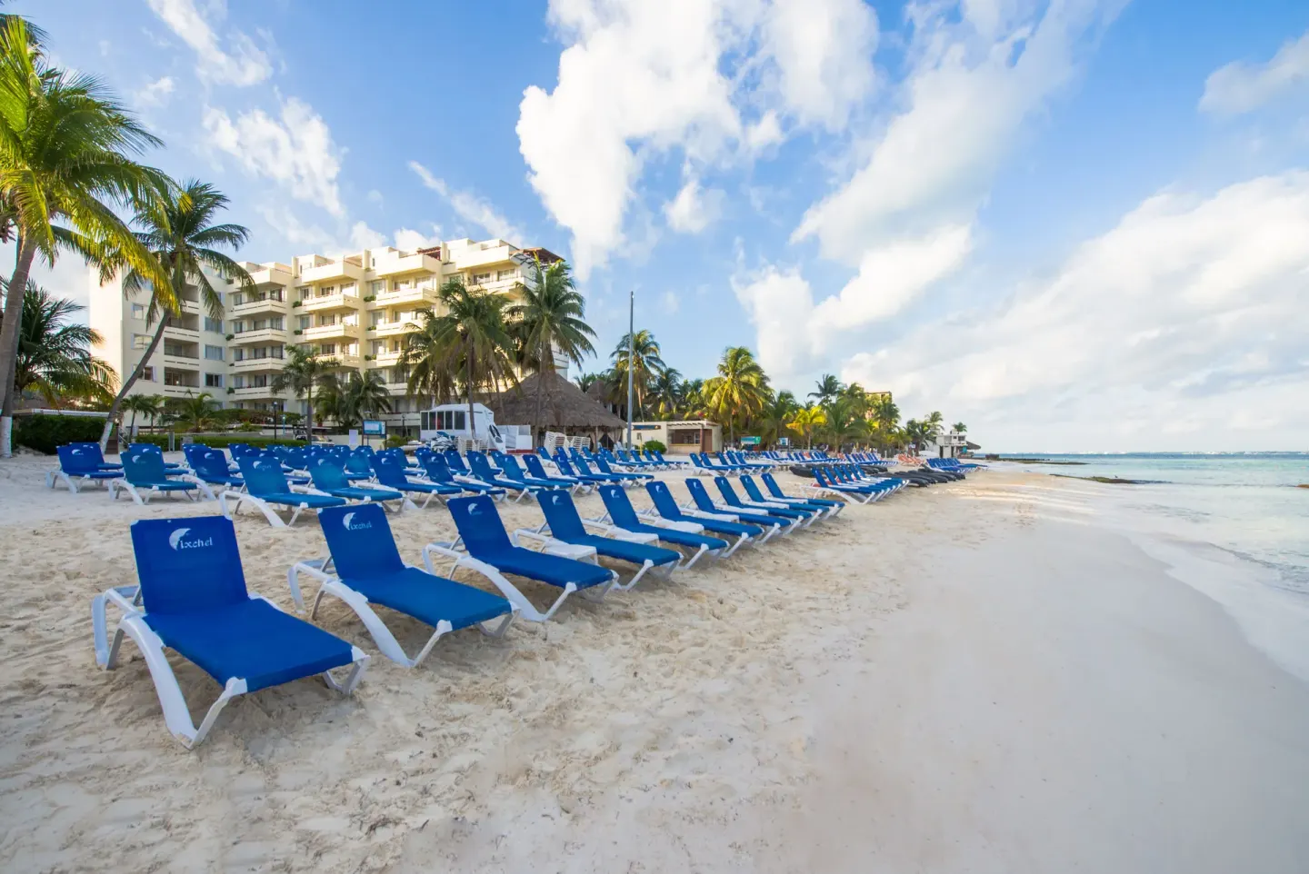 Blue beach loungers line the sand in front of Ixchel Beach Hotel.