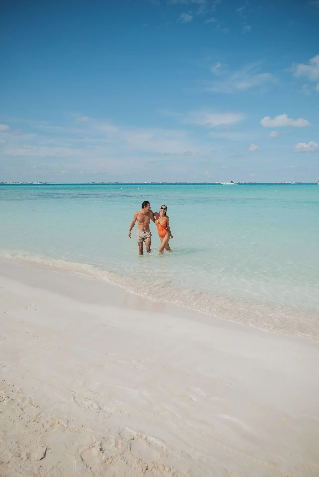 Couple wades in clear turquoise water off the beach at Ixchel Beach Hotel.