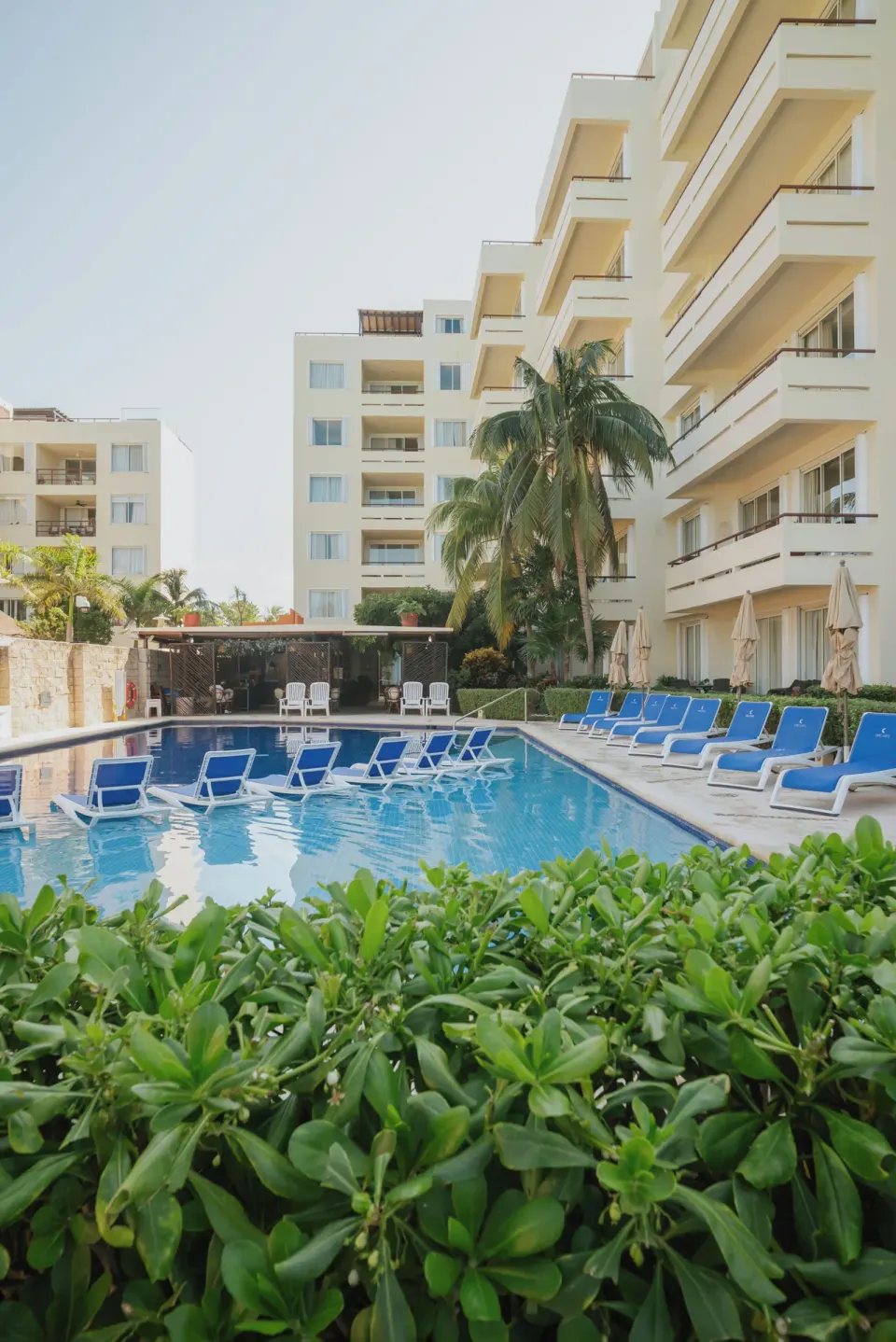 Resort pool with blue loungers and hotel balconies at Ixchel Beach Hotel.