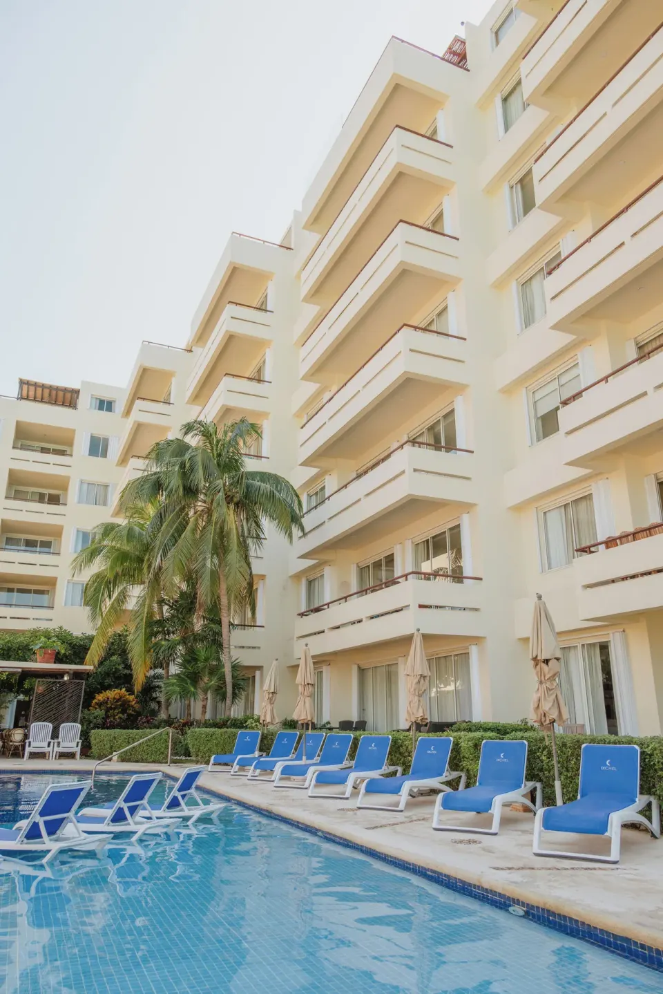 Pool deck with blue loungers below balconies at Ixchel Beach Hotel.