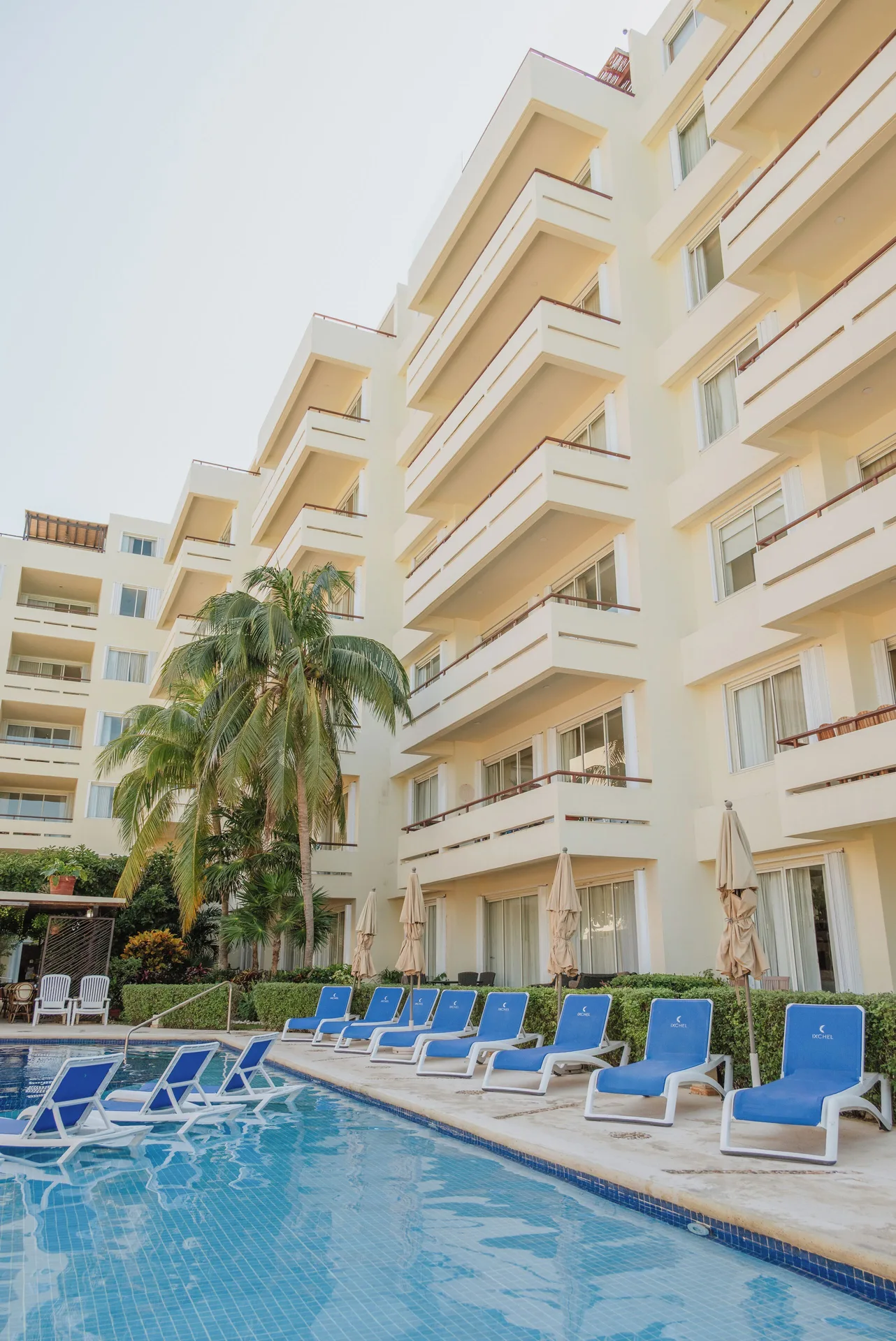 Pool deck with blue loungers below balconies at Ixchel Beach Hotel.