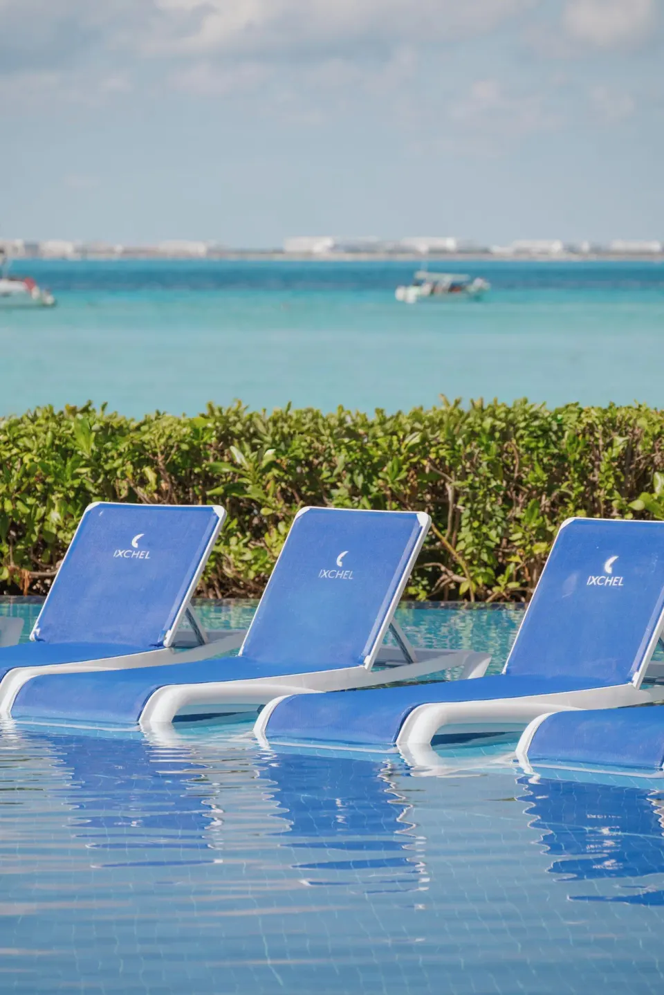 Blue pool loungers face turquoise water at Ixchel Beach Hotel.