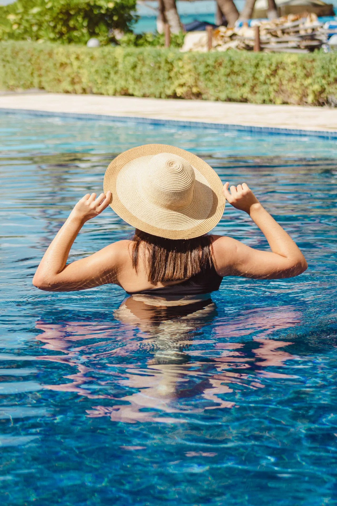 Guest wearing a sun hat standing in the pool at Ixchel Beach Hotel.