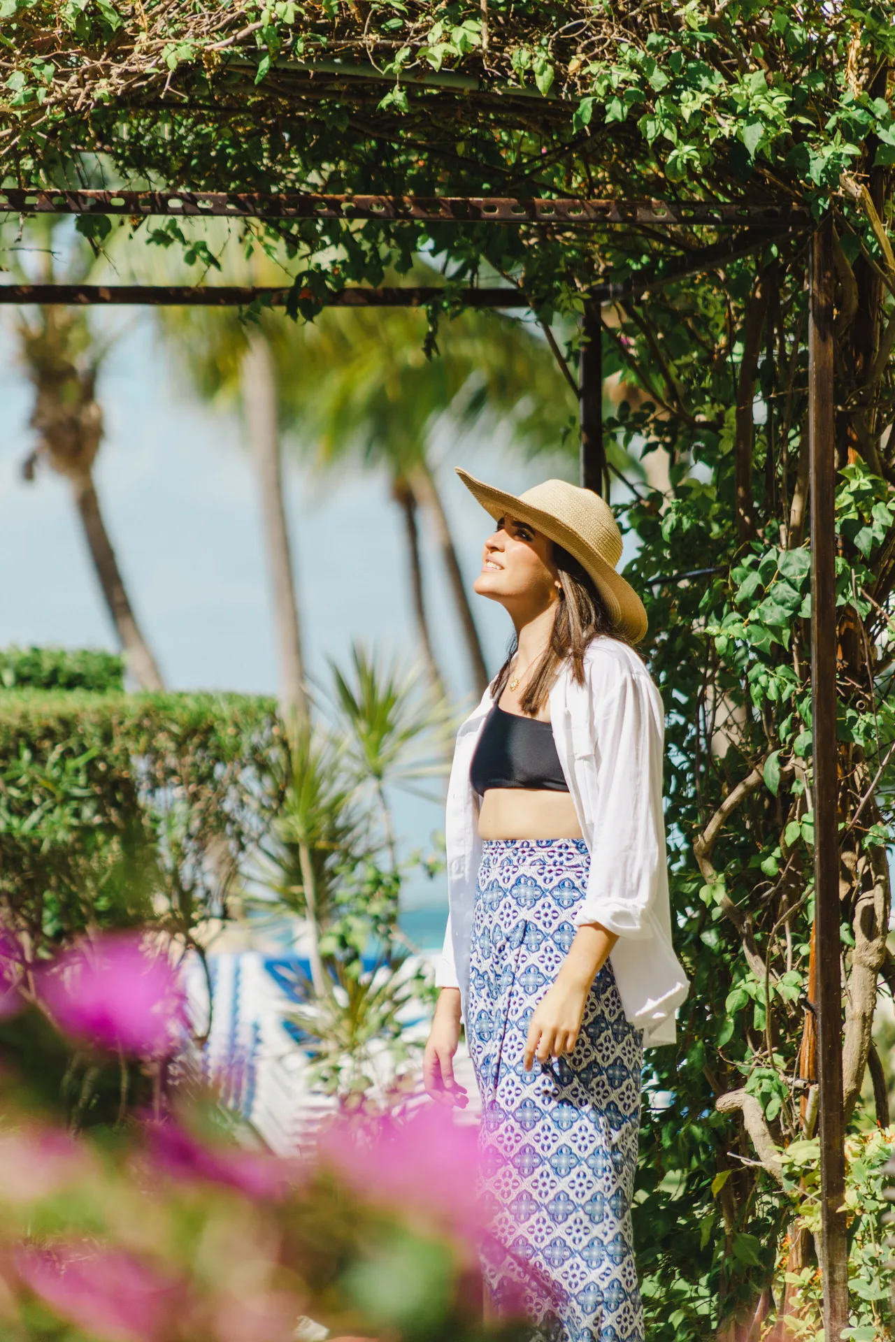 Woman under a vine-covered garden arch at Ixchel Beach Hotel.