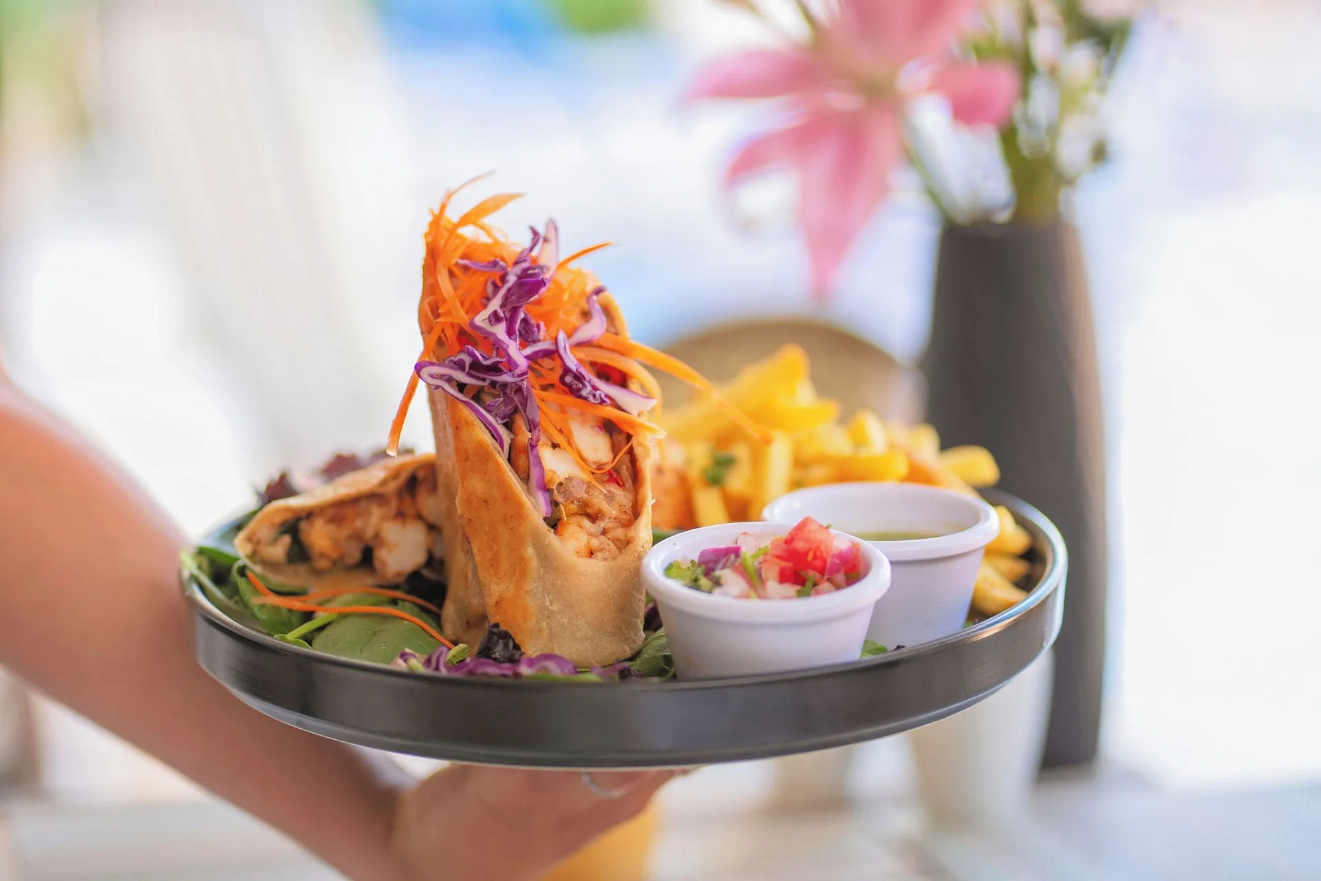 Hand-held plate with tacos, fries, salsa, and sauce at Ixchel Beach Hotel.