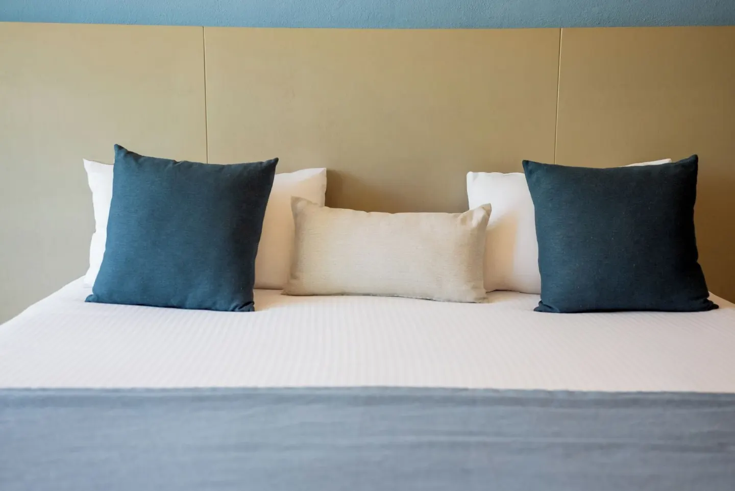 Close-up of a Standard Room bed with blue and white pillows at Ixchel Beach Hotel.