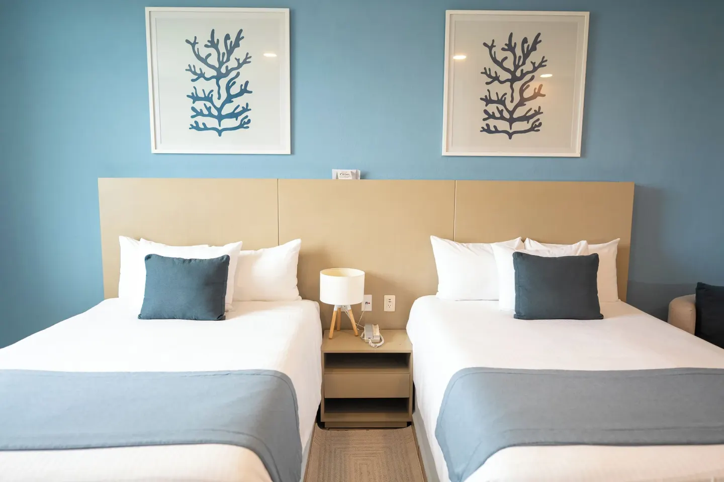 Two beds with blue accents in a Standard Room at Ixchel Beach Hotel.