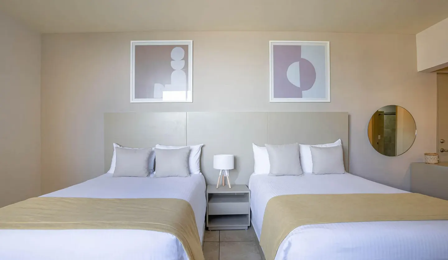 Two beds with white linens in a Standard Room at Ixchel Beach Hotel.