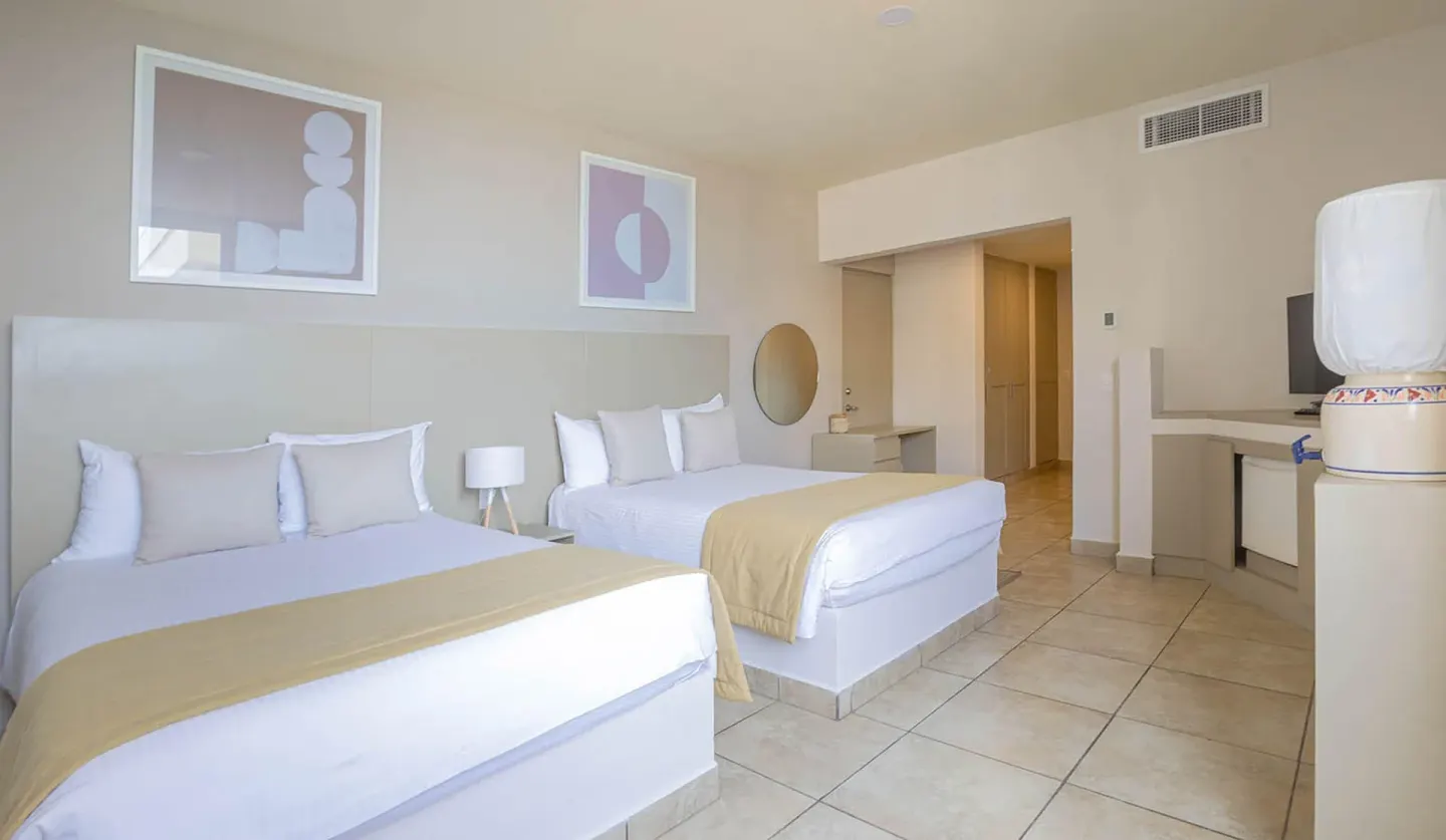 Standard Room at Ixchel Beach Hotel with two beds, tile floor, and kitchenette area.