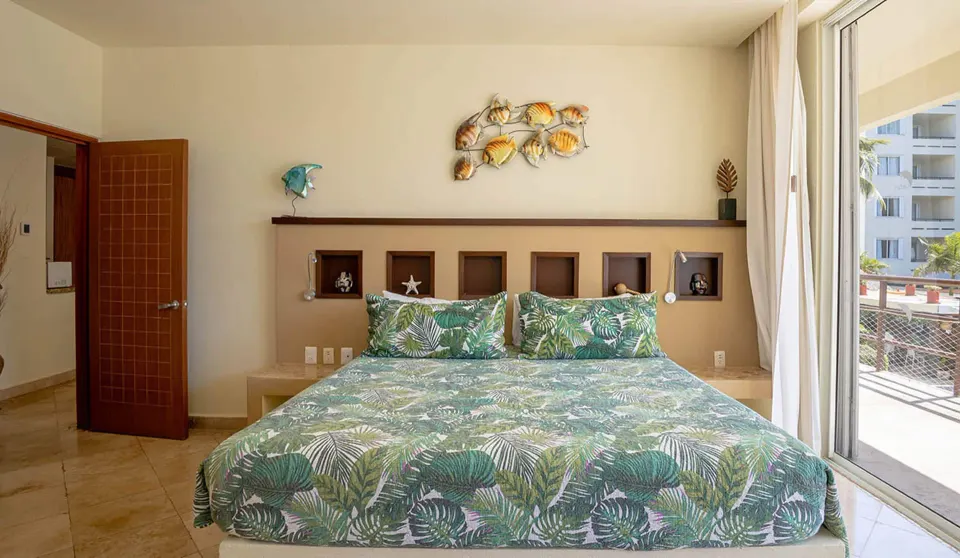 King bed with tropical bedding in a one-bedroom beachfront suite at Ixchel Beach Hotel.
