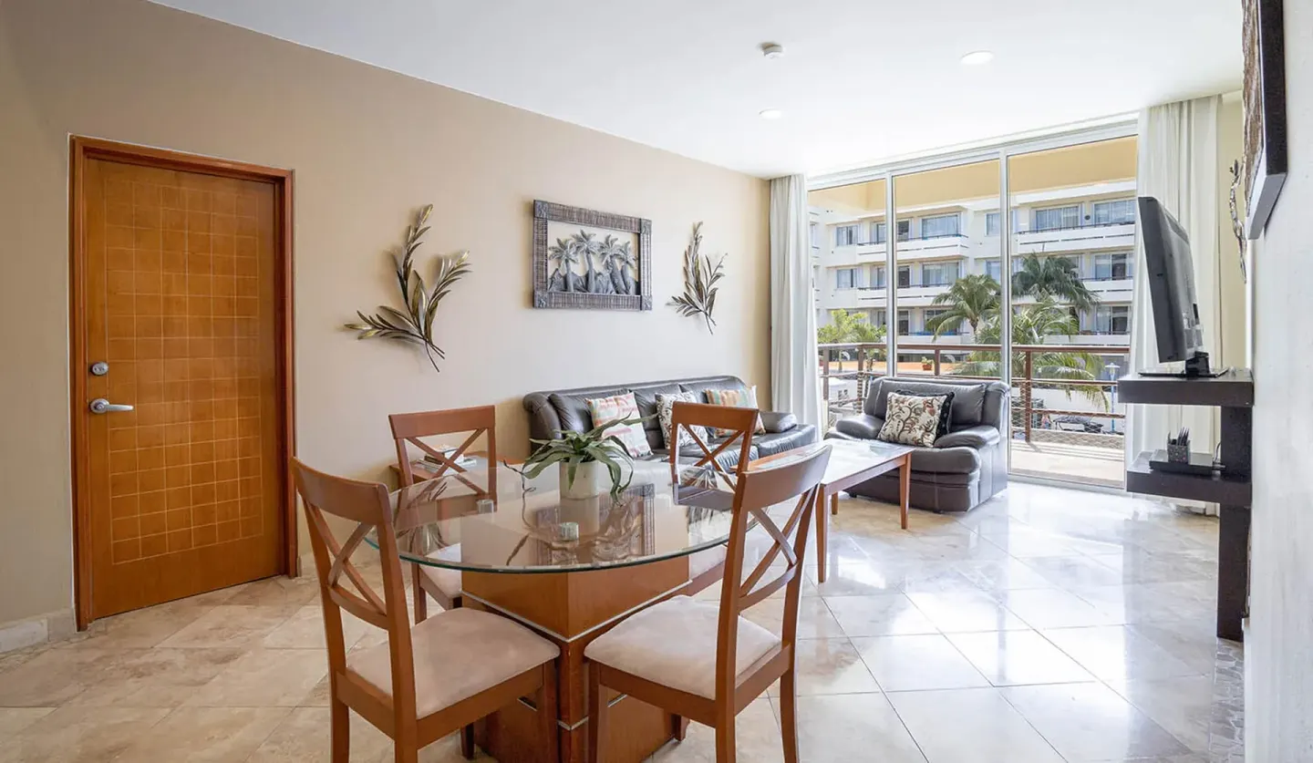 Living and dining area with balcony windows in a beachfront suite at Ixchel Beach Hotel.