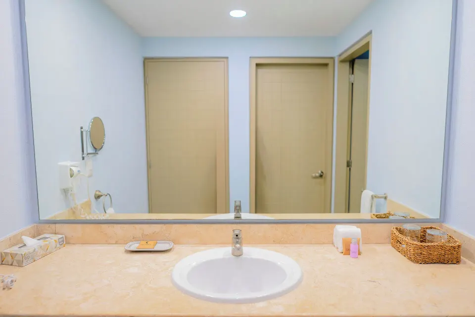 One Bedroom Suite bathroom vanity with mirror and toiletries at Ixchel Beach Hotel.