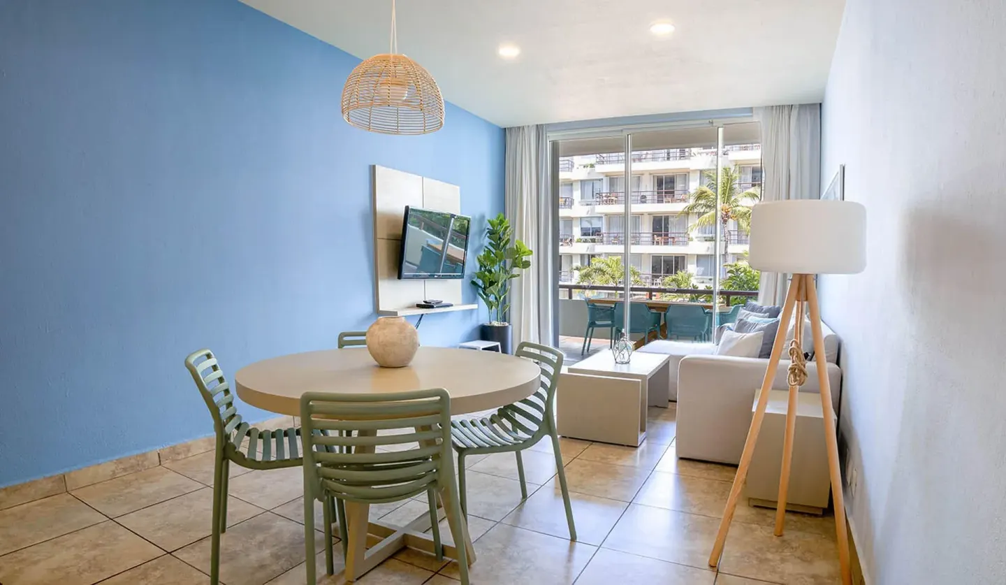 One Bedroom Suite dining and sitting area with balcony doors at Ixchel Beach Hotel.