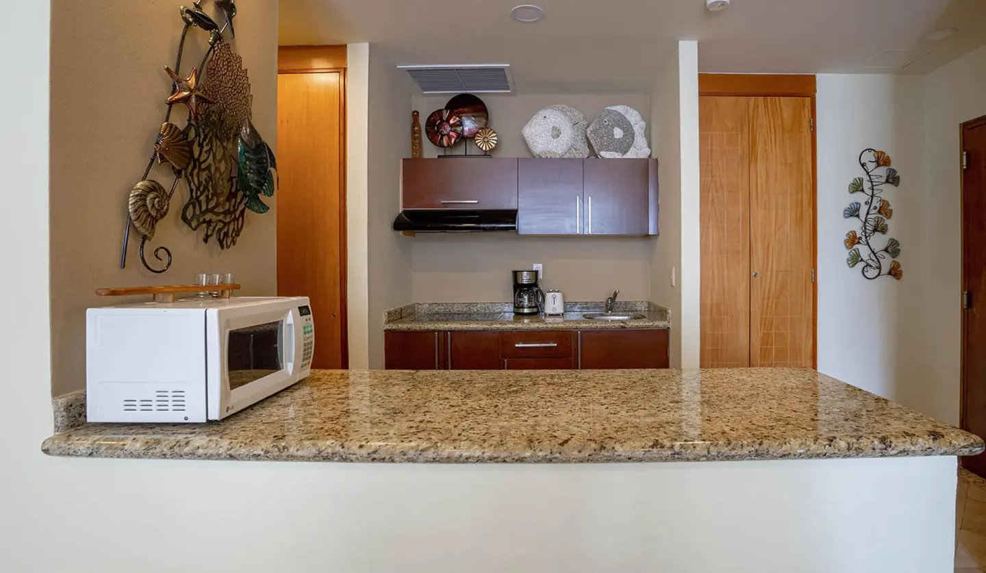 One Bedroom Suite kitchenette with granite counter and microwave at Ixchel Beach Hotel.
