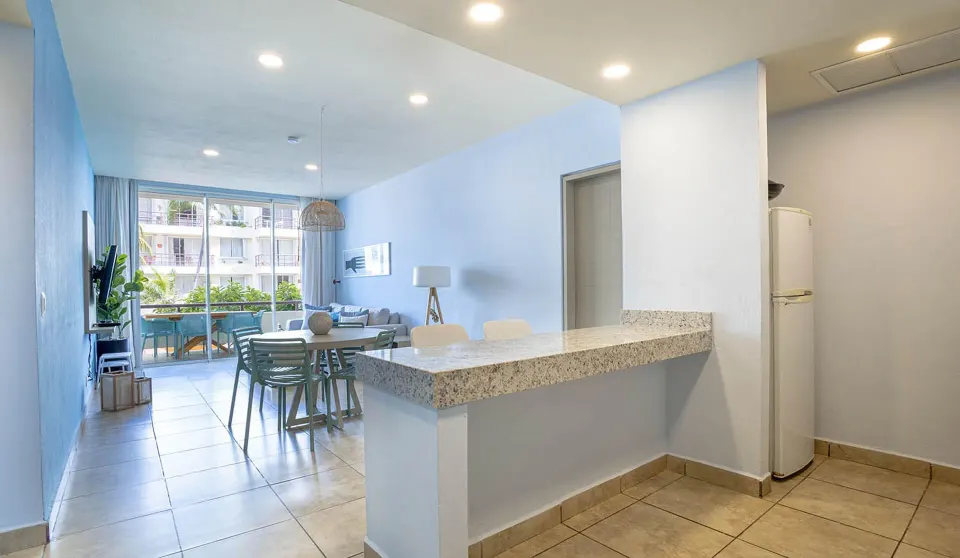 One Bedroom Suite living area and breakfast bar opening to a balcony at Ixchel Beach Hotel.