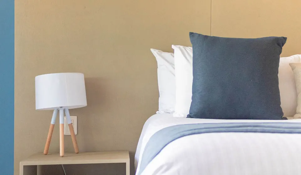 Close-up of a king bed and bedside lamp in a one-bedroom suite at Ixchel Beach Hotel.