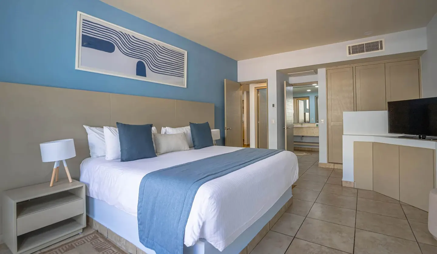 One-bedroom suite at Ixchel Beach Hotel with a king bed, TV cabinet, closet and vanity area.