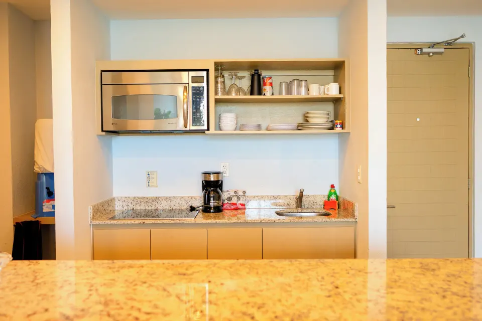 Kitchenette in a one-bedroom suite at Ixchel Beach Hotel with microwave, dishes, coffee maker and sink.
