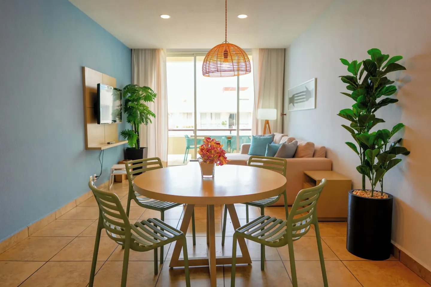Living and dining area of a one-bedroom suite at Ixchel Beach Hotel with sofa, table and balcony doors.