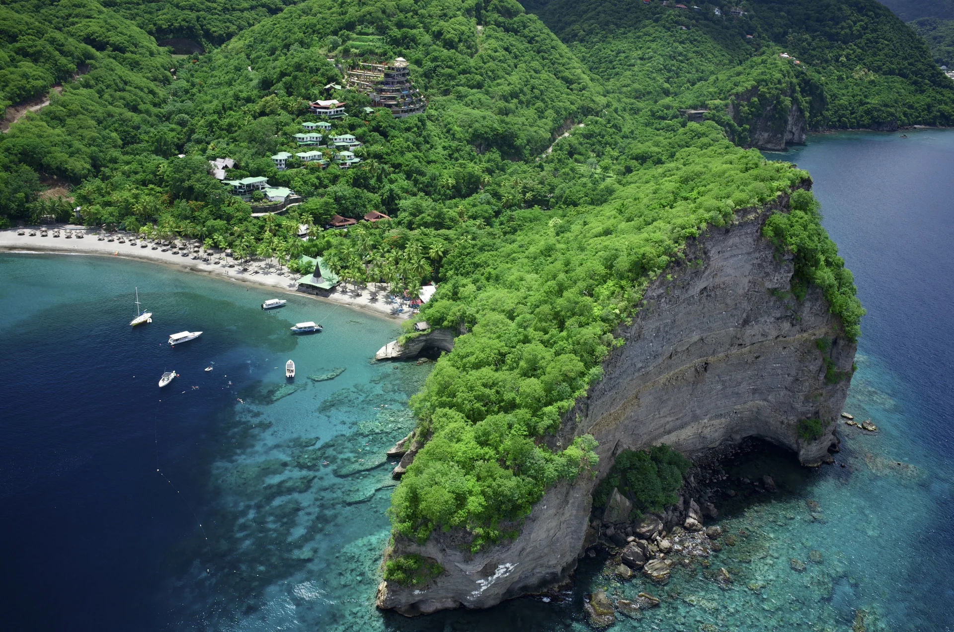 Aerial view of the beach, cliffs, and hillside resort buildings at Jade Mountain Resort.