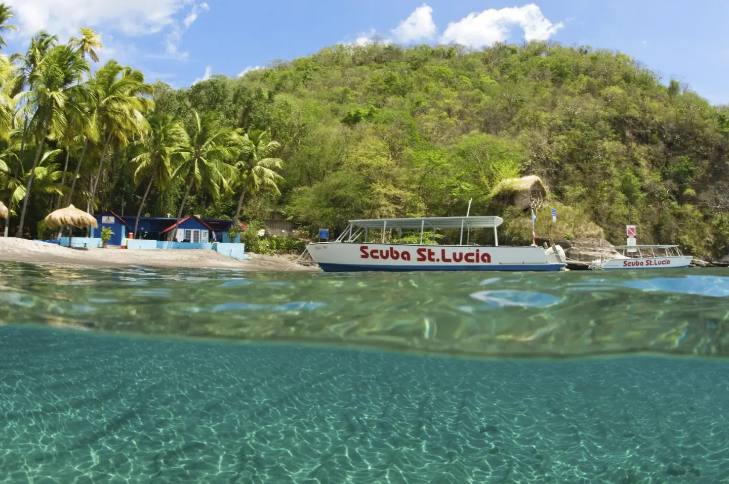 Clear water, a beach, and dive boats appear along the shore at Jade Mountain Resort.