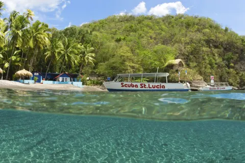 Clear water, a beach, and dive boats appear along the shore at Jade Mountain Resort.