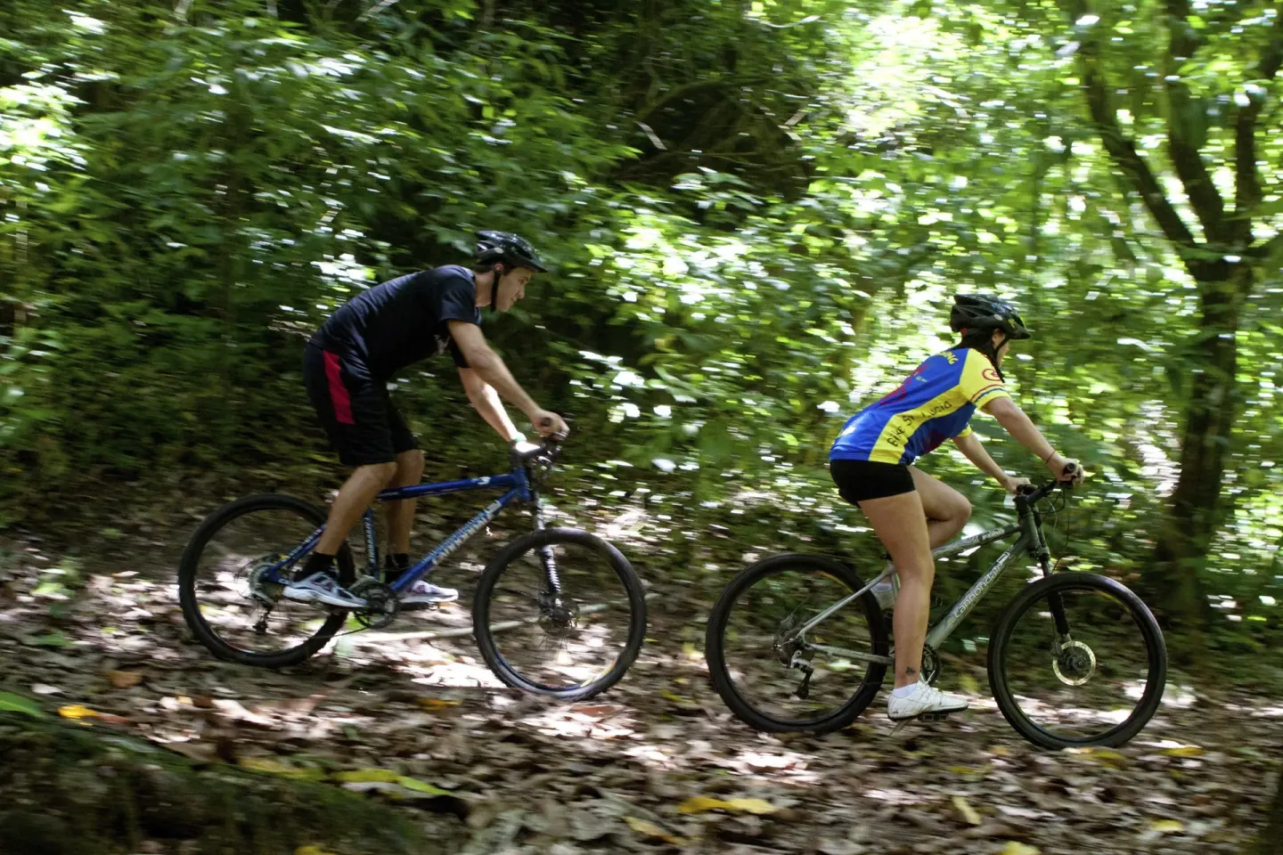 Two cyclists ride a shaded forest trail during an outing at Jade Mountain Resort.