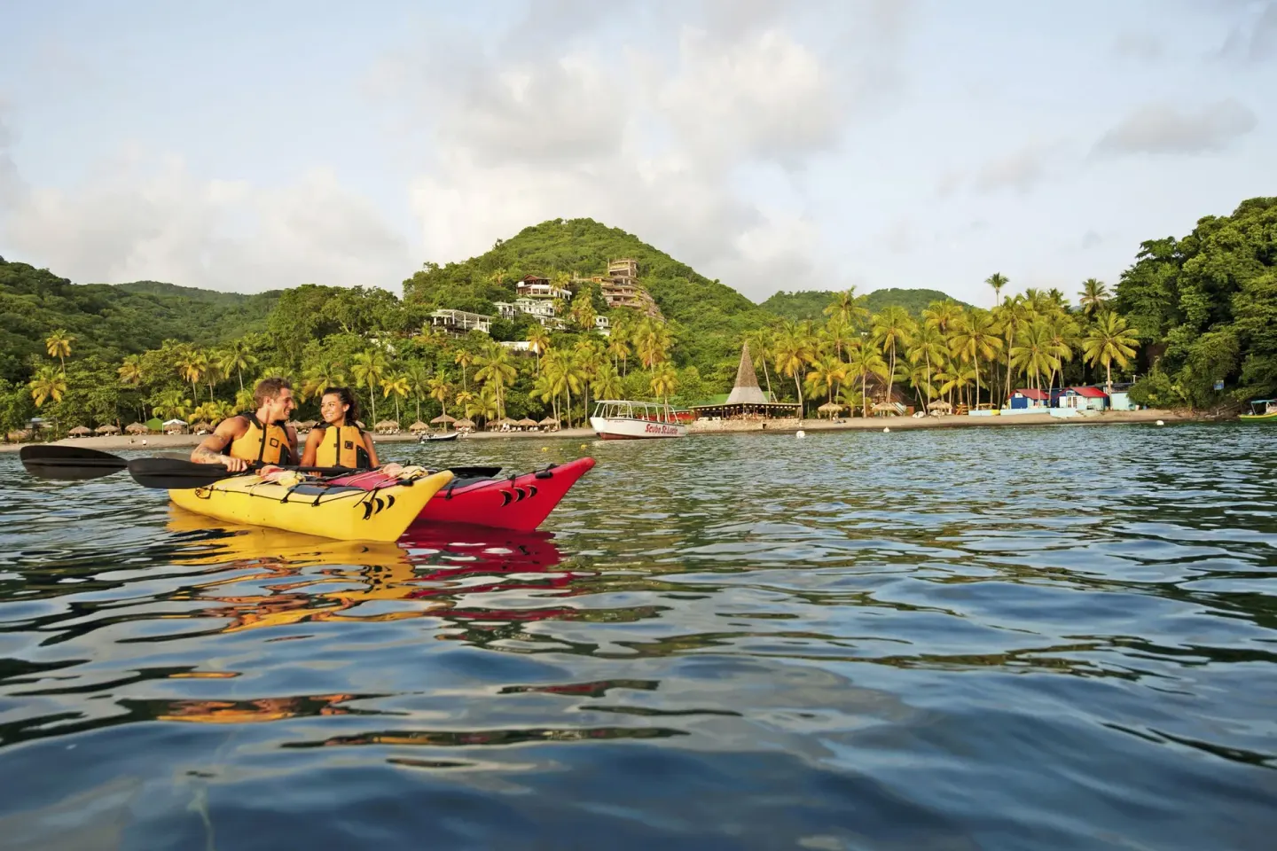 Guests kayak on calm water near the palm-lined shore at Jade Mountain Resort.