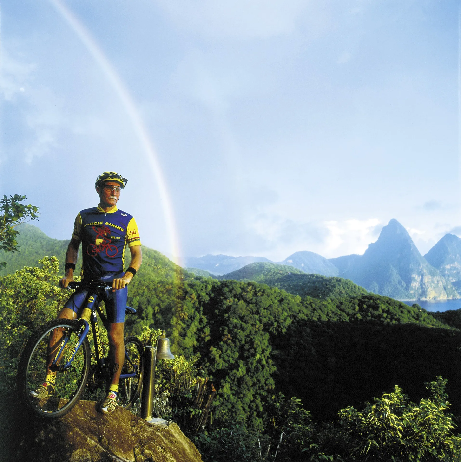 A mountain biker overlooks forested hills and the Pitons near Jade Mountain Resort.