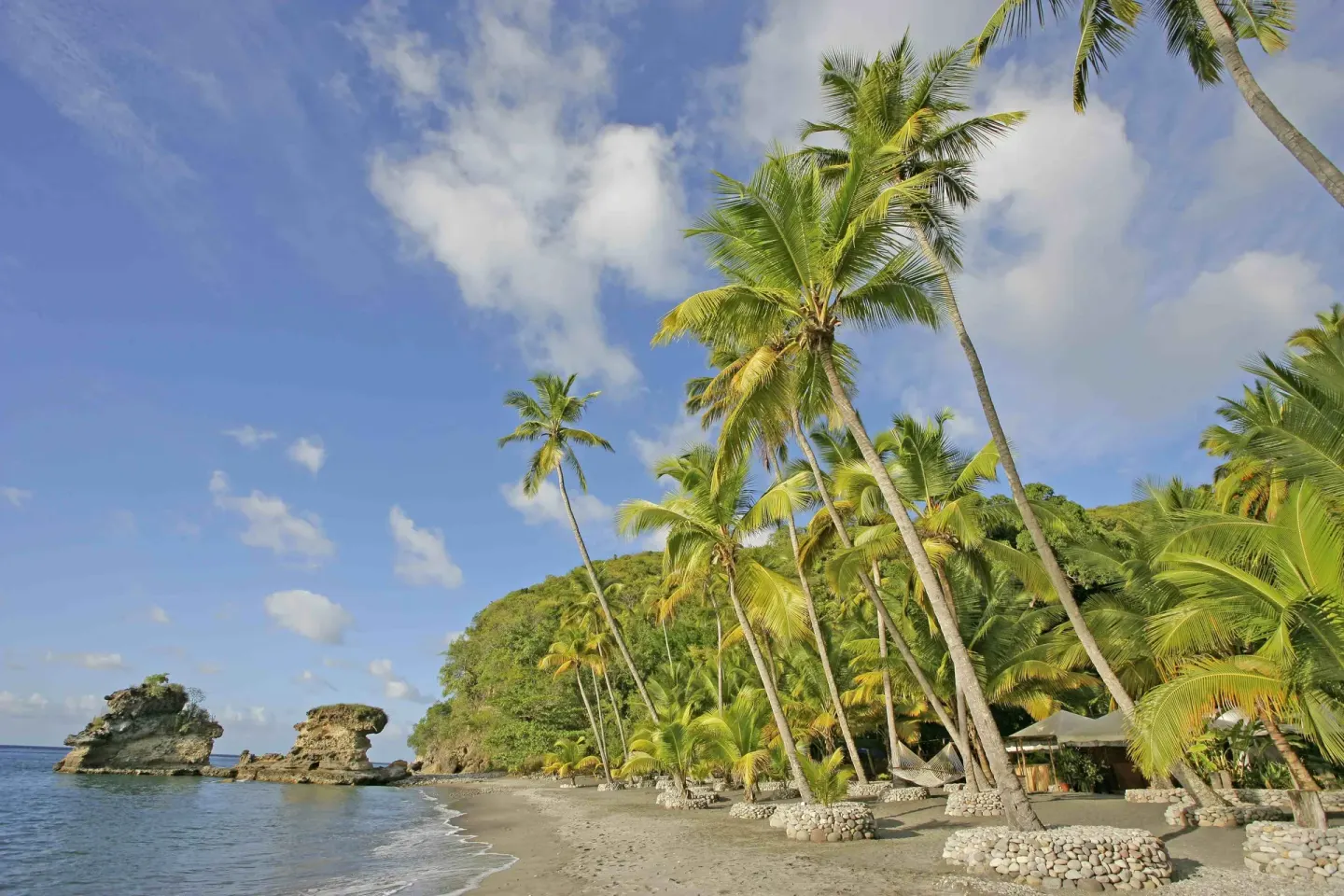 Palm-lined beach with rock formations and calm water at Jade Mountain Resort.
