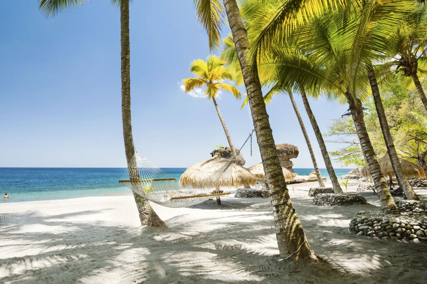 Palm-shaded beach hammock and thatched umbrellas at Jade Mountain Resort.