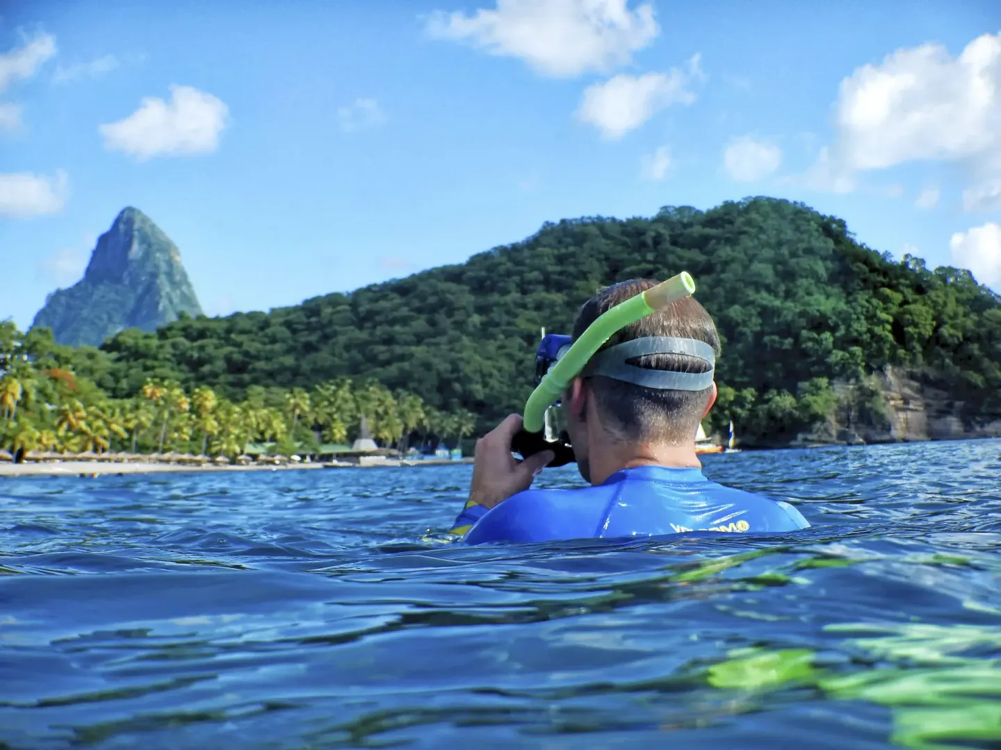 A snorkeler floats at the surface facing the shoreline at Jade Mountain Resort.