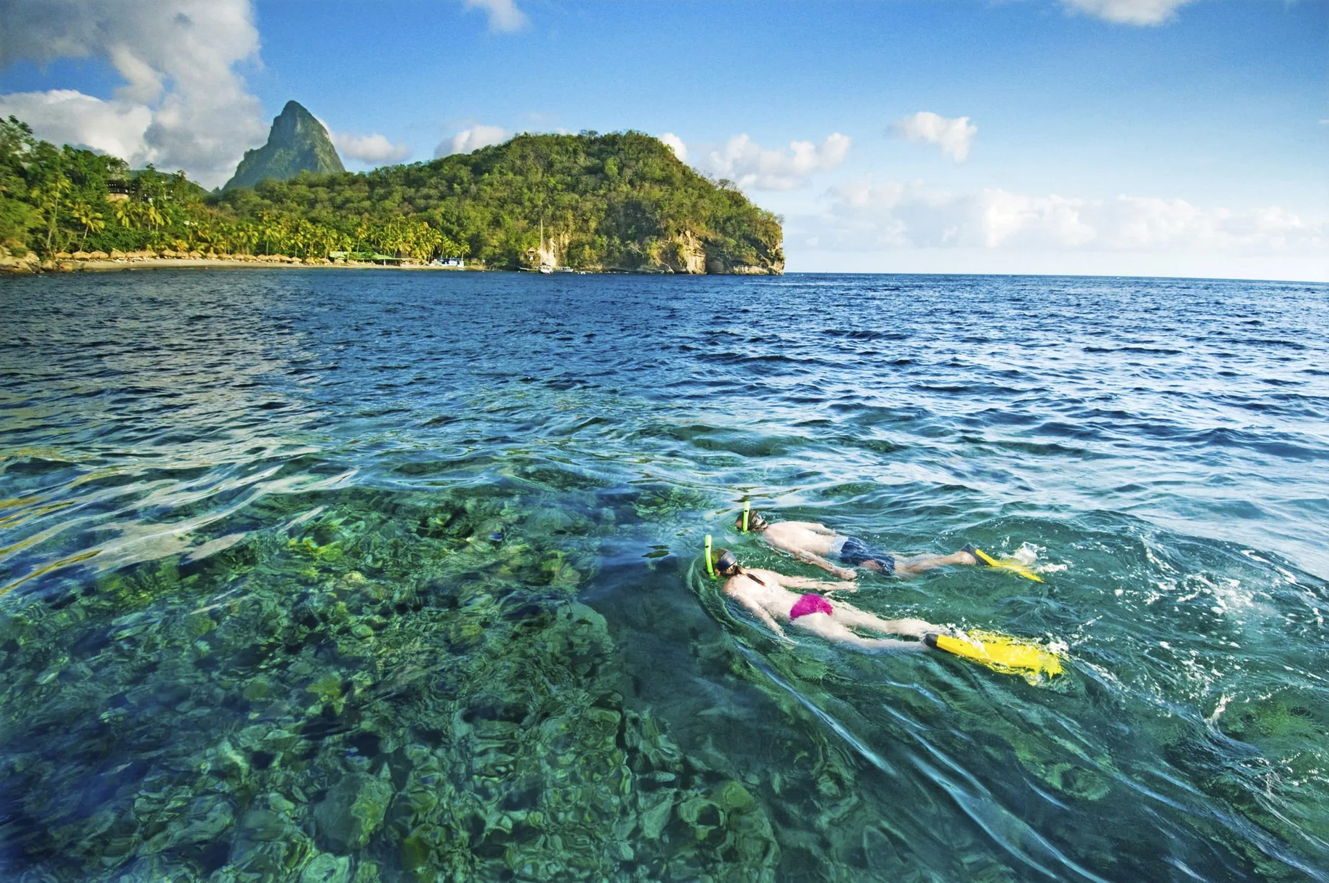 Two snorkelers swim over clear reef water near Jade Mountain Resort.