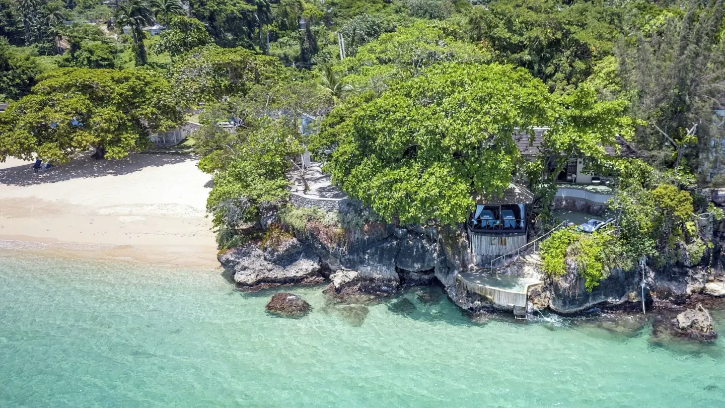 Aerial view of beach, rocky shoreline, trees, and clear water at Jamaica Inn.