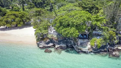 Aerial view of beach, rocky shoreline, trees, and clear water at Jamaica Inn.