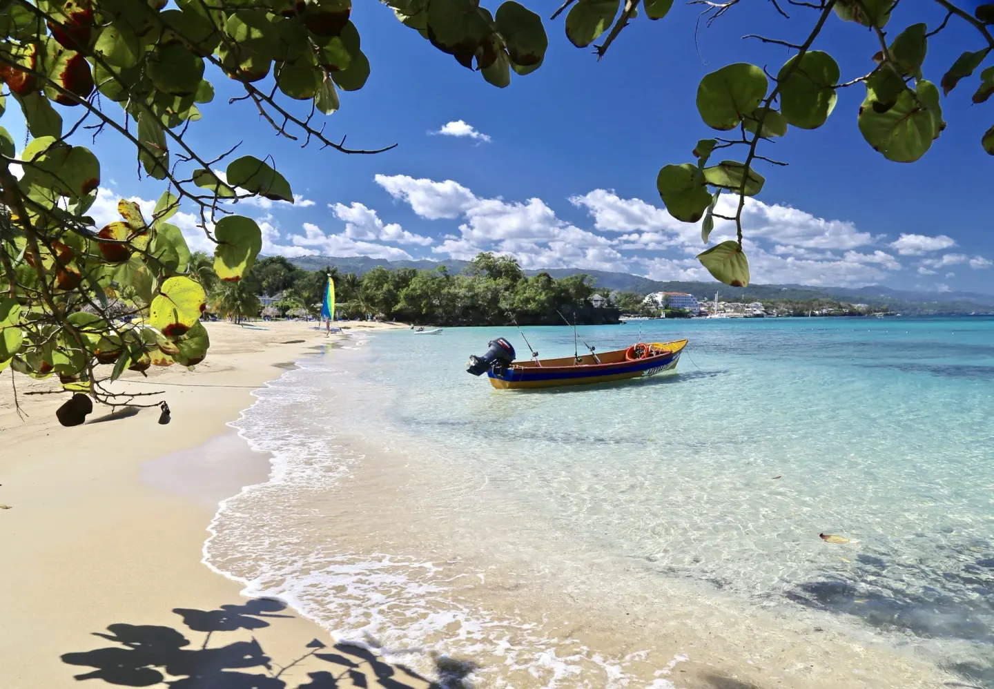 A small boat floats in clear water along the beach at Jamaica Inn.