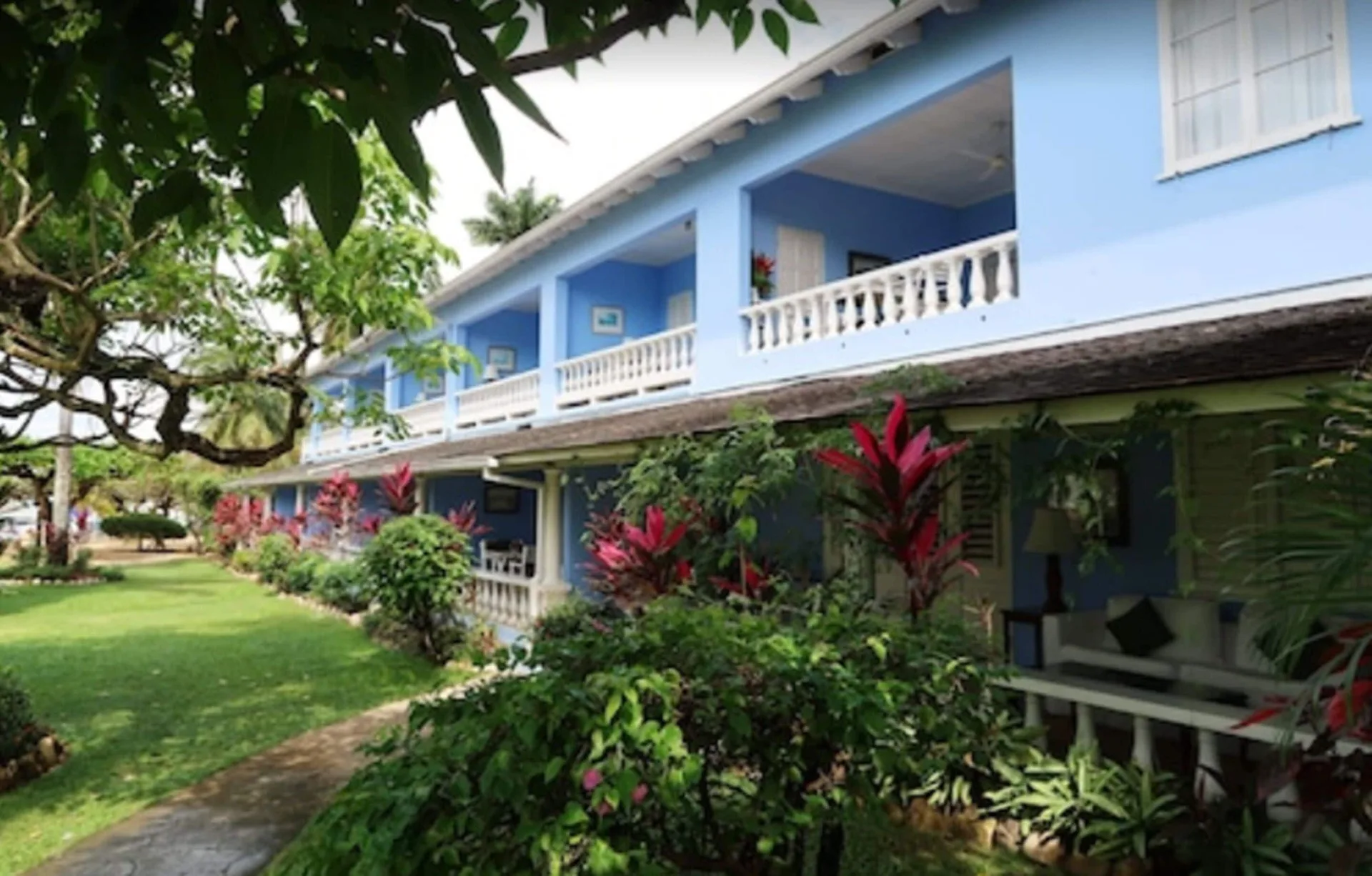 Blue two-story guest building with white balconies and tropical landscaping at Jamaica Inn.